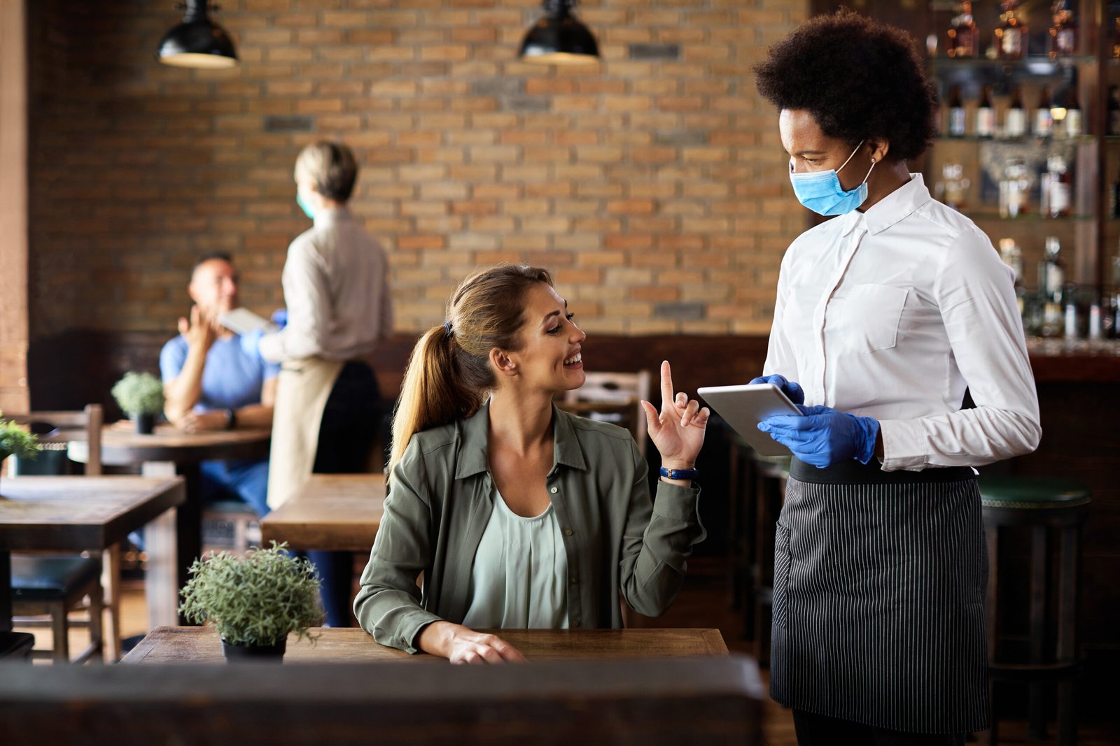 Happy woman making an order while talking to black waitress in a